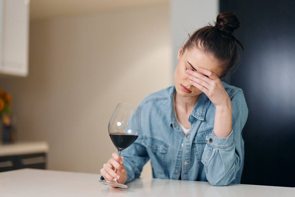 Одинокая предосторожность: одинокая женщина пьет вино в меланхолическом ресторане - Фото, изображение