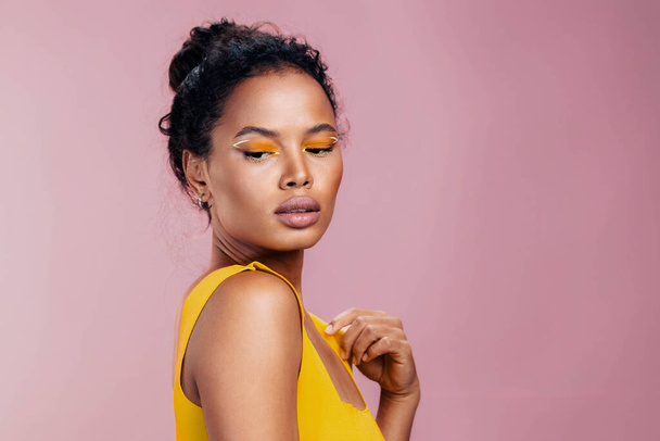 Nő kreatív arc stúdió kozmetika gyönyörű kozmetikai szépség rózsaszín tér smink stílus sárga afrikai bőr etnikai divat mosoly szem színes másolat portré fekete modell - Fotó, kép