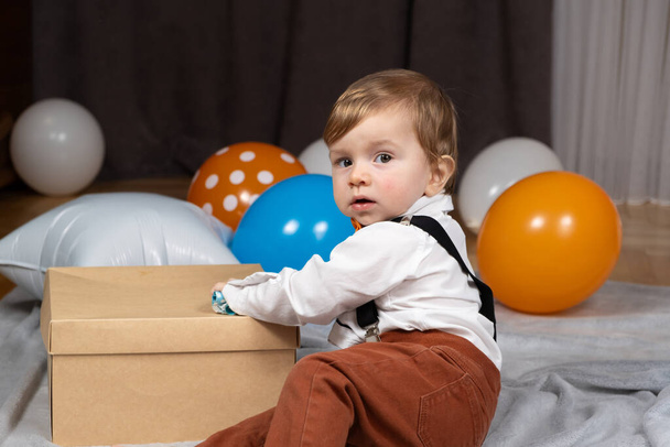 Pikkulapsi juhlii ensimmäistä syntymäpäiväänsä ilmapallojen joukossa.. - Valokuva, kuva