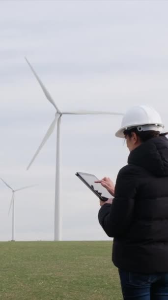 woman engineer with tablet  computer working in countryside with wind turbines - Záběry, video