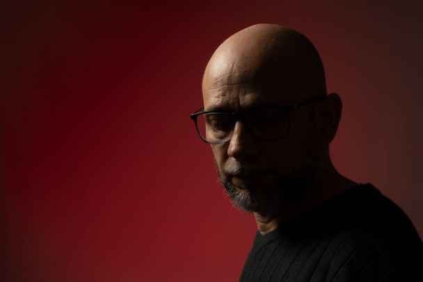 Handsome, bald, bearded man in prescription glasses looking down. Isolated on pink background. - Photo, Image