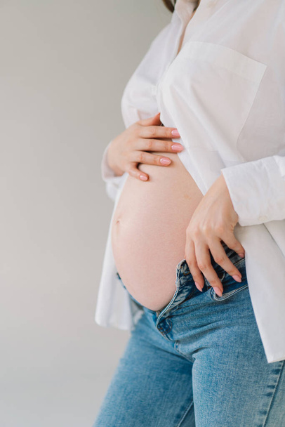 Egy terhes nő hasa. Egy terhes nő hasáról készült kép. nő vár egy újszülött baba. Terhes nő megérinti a hasát a házban - Fotó, kép