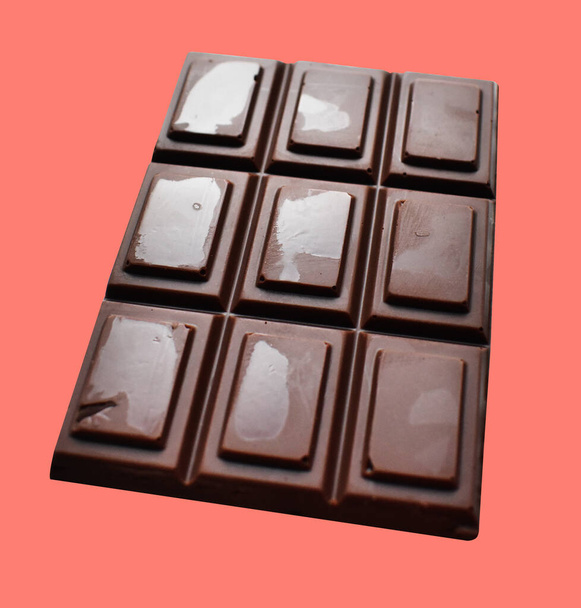 Barra de chocolate con leche aislada con camino de recorte, sin sombra en el fondo rosa, ingrediente de cocina, postre dulce casero - Foto, Imagen