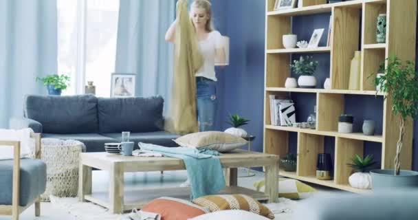 Woman, tidy and spring cleaning living room for housework, wellness and pride in home. Young person, folding blankets and pack cushions of housekeeping in lounge on weekend and chores in apartment. - Footage, Video