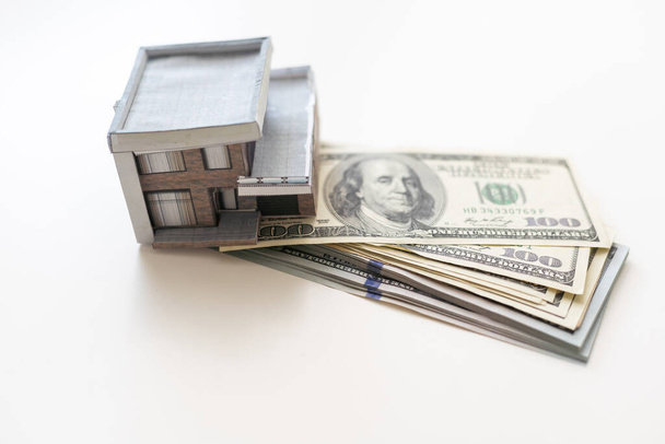 Μοντέλο σπιτιού σε χαρτονομίσματα των 100 δολαρίων. Κρατήστε τα χρήματα ή τις επενδύσεις για την οικοδόμηση ενός νέου σπιτιού. - Φωτογραφία, εικόνα