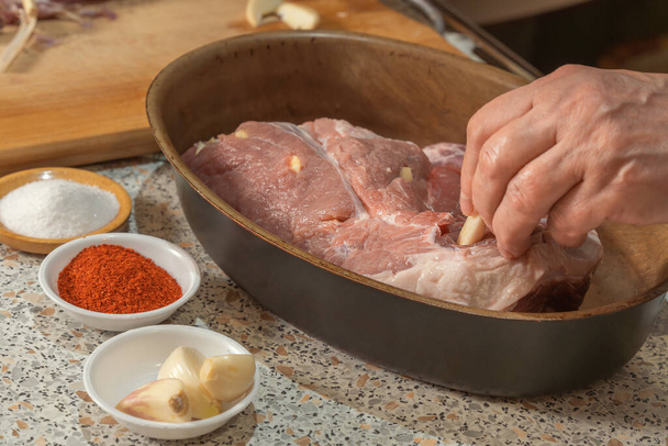 Το χέρι του μάγειρα γεμίζει ένα κομμάτι ωμό κρέας που παρασκευάζεται για το ψήσιμο με σκόρδο. σπιτικό φαγητό - Φωτογραφία, εικόνα