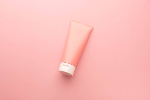 Tubo de plástico de botella de exprimidor rosa en blanco sobre fondo rosa. Embalaje de crema, loción, gel, cuidado de la piel de espuma facial. Marca cosmética del producto de la belleza. - Foto, imagen