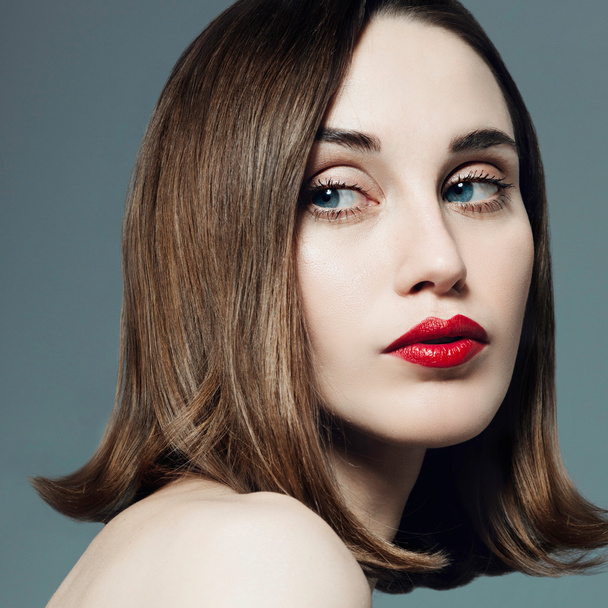 Portrait of beautiful girl with red lipstick in the studio on a gray background - Zdjęcie, obraz