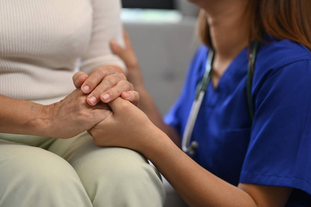 希望とサポートのためにシニア女性の手を握っている介護看護師のクロップショット. 高齢者医療コンセプト - 写真・画像