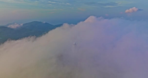 aerial view The Big Buddha of Phuket can only be seen as the head peeking out from the sea of mist..Phuket Big Buddha in the thick white mist. .A fluffy mist covers the Big Buddha in Phuket. - Materiaali, video
