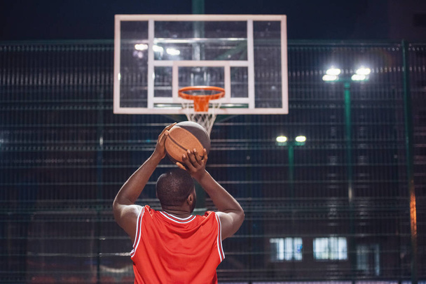 Krásný basketbalový hráč hraje basketbal venku večer - Fotografie, Obrázek