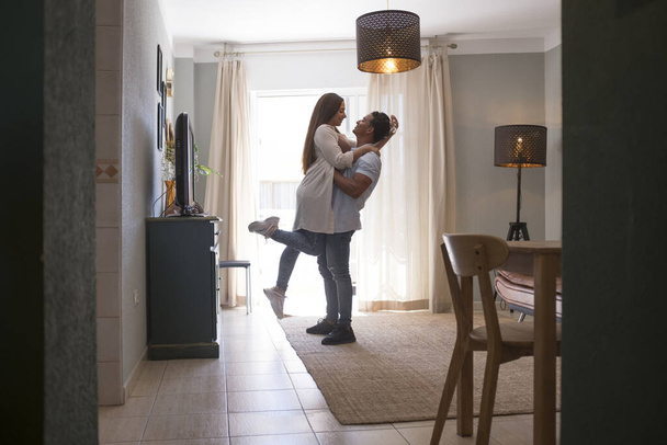 Full length of carefree young couple dancing at home together - 写真・画像