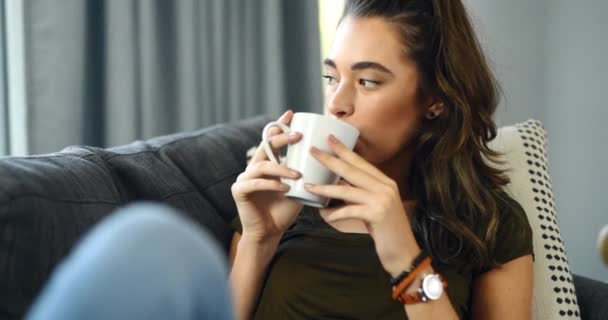 Woman, sofa and thinking with coffee, home and relax with happy memory, vision and peace in living room. Girl, tea cup and smile on lounge couch with ideas, remember or choice with drink in apartment. - Footage, Video