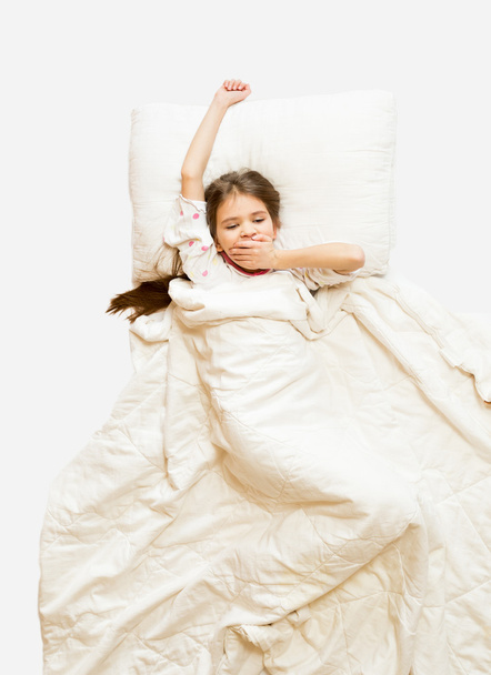 isolierte Aufnahme eines kleinen Mädchens, das morgens im Bett gähnt - Foto, Bild