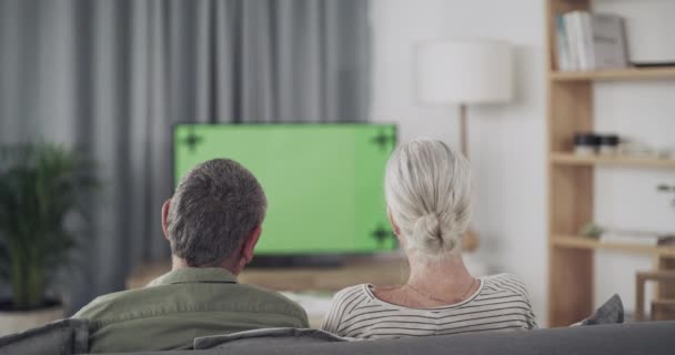 Ζευγάρι, καναπές και βλέποντας τηλεόραση στην πράσινη οθόνη με τηλεχειριστήριο για ταινίες ή επιλογή ταινιών και υπηρεσία streaming στο σπίτι. Πίσω από τους ανθρώπους να χαλαρώσετε στον καναπέ ή σαλόνι με τηλεόραση mockup για διακοπές ή το Σαββατοκύριακο. - Πλάνα, βίντεο