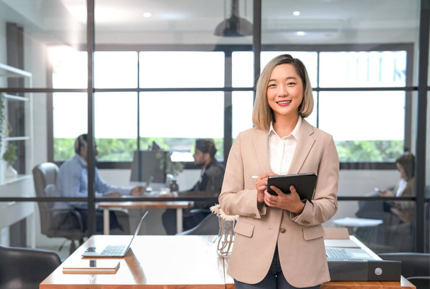 concepto de gente de negocios estilo de vida trabajando en el lugar de trabajo, retrato joven mujer de negocios asiática sonriendo, sosteniendo tableta digital, de pie en la sala de oficina  - Foto, imagen