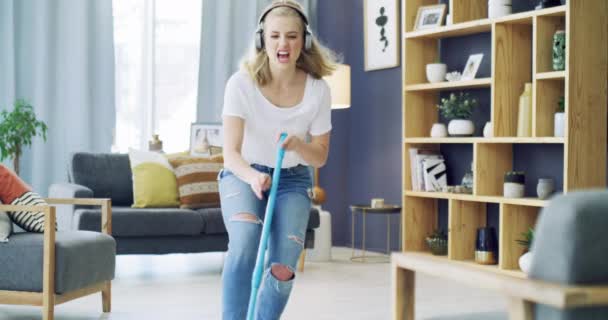 Cleaning, singing and a woman with headphones for music in a house for fun energy and housework. Young female person in her apartment home with happiness, dancing and joy to mop and clean floor. - Footage, Video