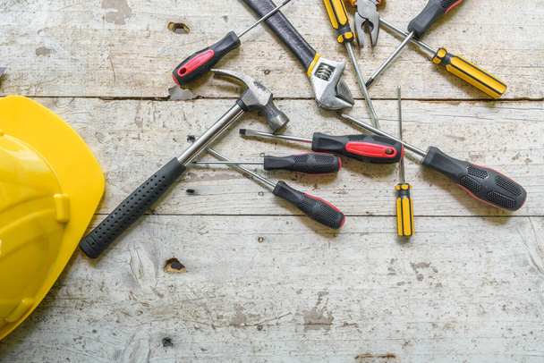 sortimento de ferramentas manuais bem utilizadas espalhadas por uma superfície de madeira desgastada, indicativas de um espaço de trabalho ou de uma bancada. - Foto, Imagem