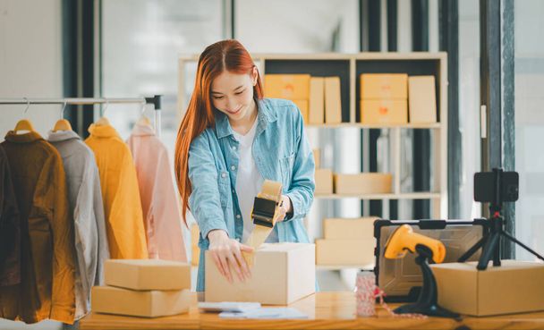 Online small business owners are packing their ordered products into the boxes for their customers based on the concept of online shopping - online shopping. - Foto, Bild