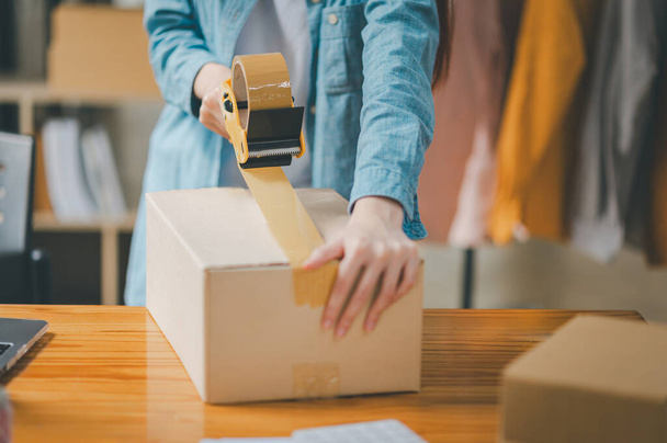 Online small business owners are packing their ordered products into the boxes for their customers based on the concept of online shopping - online shopping. - Foto, Bild