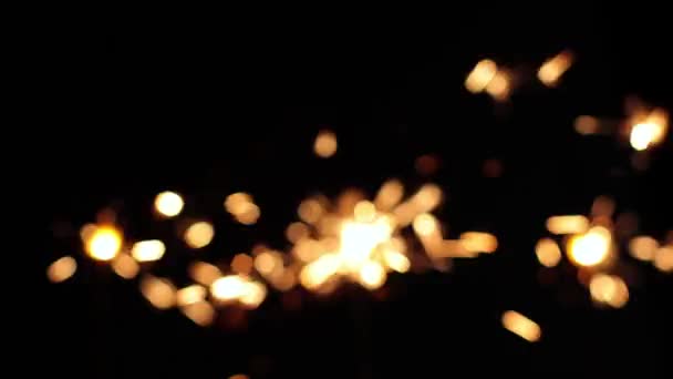 Gelukkig Nieuwjaar! Bengaalse lichten. Licht op een zwarte achtergrond, feest. Feest in een donkere kamer, close-up van de lichten. Vonken branden, vakantie en vuurwerk. Het gloeit prachtig. - Video