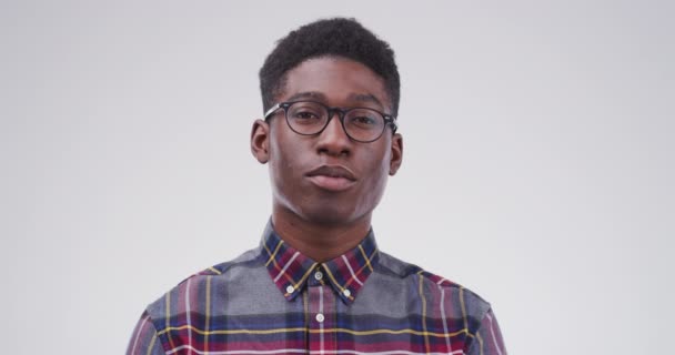 Serieuze zwarte man, bril en gezicht van nerd of nerd geïsoleerd tegen een studio achtergrond. Portret van slim Afrikaans persoon of casual model op zoek met bril, blanco blik of brillen op mockup. - Video