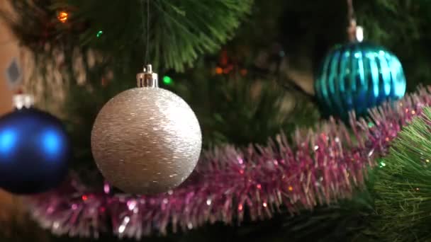 A fényes karácsonyfa dísz forog, miközben lóg a karácsonyfa. - Felvétel, videó