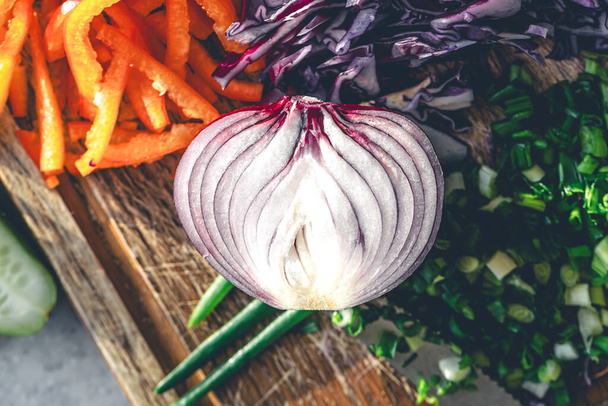 Close-up, meia cebola em uma tábua de redução com verduras frescas de salada. Cebola vermelha na tábua de corte na cozinha. - Foto, Imagem