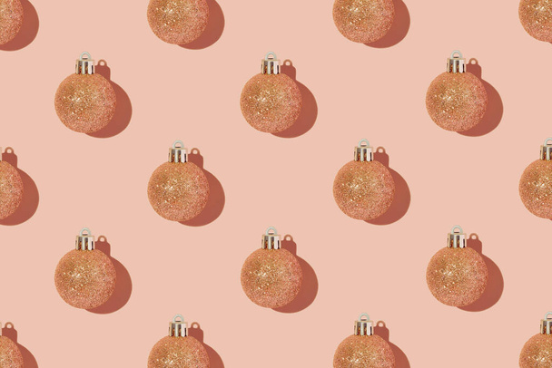 Pfirsichglänzende Christbaumkugeln auf einem pfirsichfarbenen Hintergrund. Kreatives Weihnachtsmuster - Foto, Bild