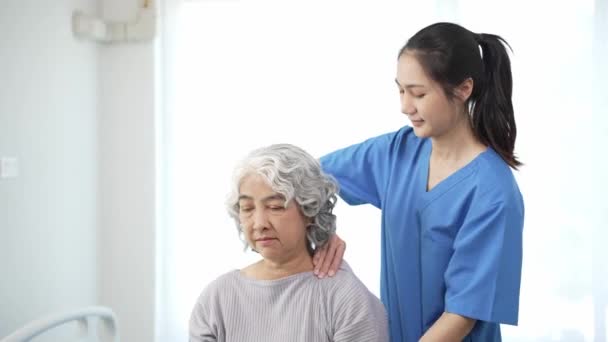 Fizioterapeuta, aki fizikoterápiát végez egy idős ázsiai nővel, aki egy női beteg sérült karjának kezelését vizsgálja, hogy rehabilitálja a fájdalmas kart egy női orvos egészségügyi koncepciójával. - Felvétel, videó
