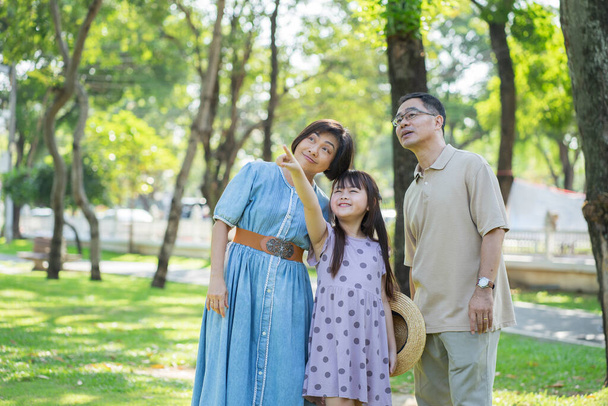 Happy Asian family enjoying leisure time with outdoor activities in a public park - Photo, Image