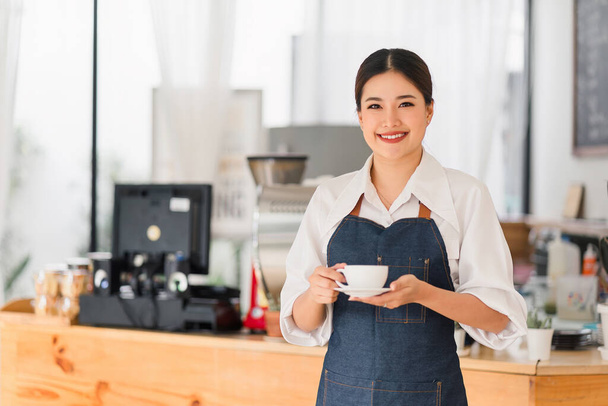 Cheerful small business owners smiling and looking at camera while standing in front of cafe entrance, welcomes guests. Business and entrepreneurs concept - Photo, image