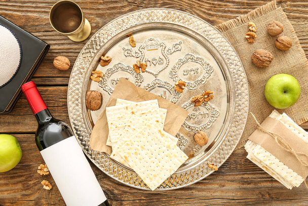 Composition with Passover Seder plate, flatbread matza, bottle of wine and walnuts on wooden background - Foto, Imagem