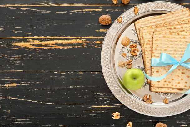 Passover Seder plate with flatbread matza, apple and walnuts on dark wooden background - Fotoğraf, Görsel