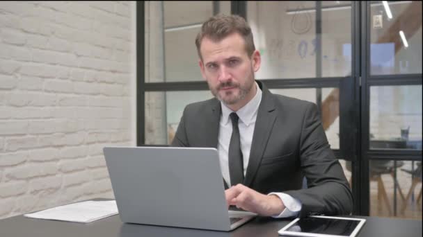 Pulgares hacia abajo por el hombre de negocios de mediana edad mientras se utiliza el ordenador portátil - Metraje, vídeo