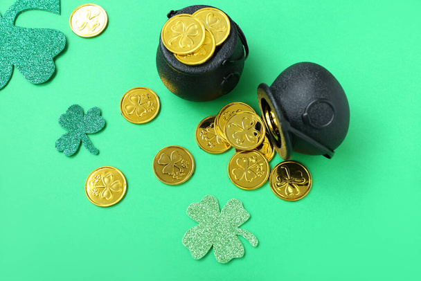 Pots with coins and paper clovers on green background. St. Patrick's Day celebration - 写真・画像