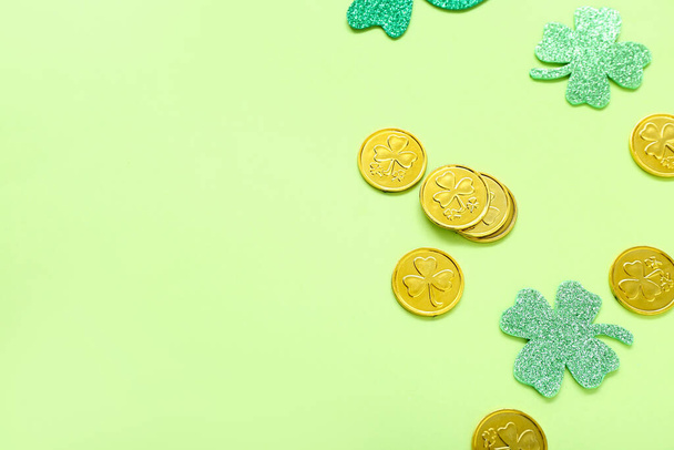 Golden coins with paper clovers on light green background. St. Patrick's Day celebration - Фото, изображение