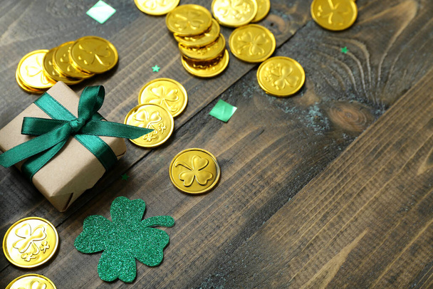 Gift with golden coins and decor on brown wooden background. St. Patrick's Day celebration - Fotografie, Obrázek
