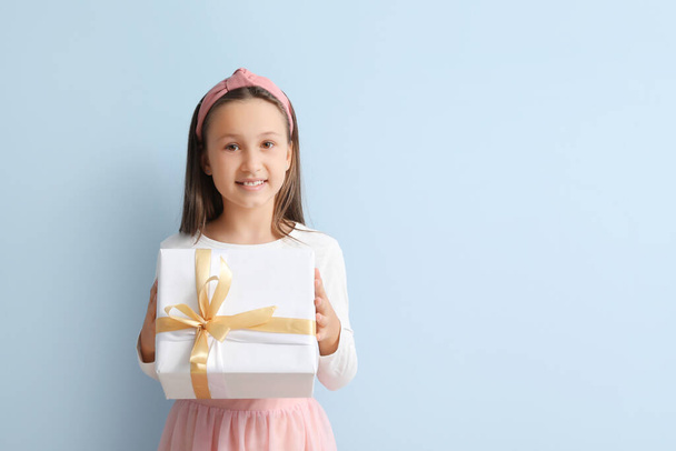 Little girl with gift on light blue background - Photo, image