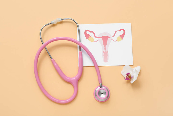 Stéthoscope avec dessin de l'utérus féminin sur fond de couleur - Photo, image