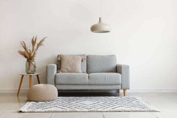Grey sofa with cushion and pampas grass on coffee table in light living room - Φωτογραφία, εικόνα