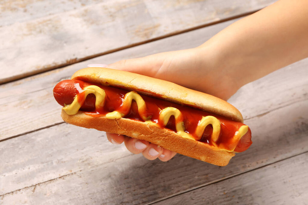 Nainen tilalla maukas hot dog harmaa puinen tausta - Valokuva, kuva