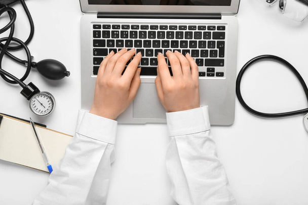 Doctor working with laptop on white background, top view - Foto, afbeelding