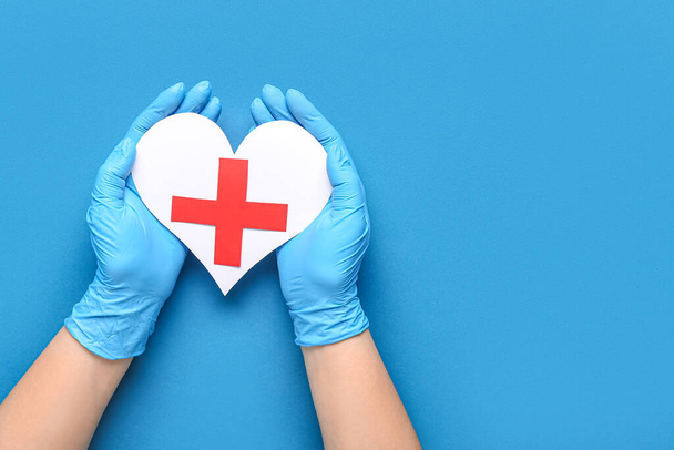 Doctor with paper heart and cross on blue background - Fotografie, Obrázek