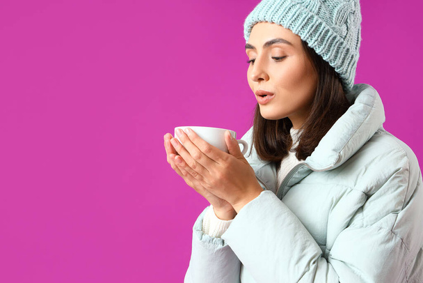 Mladá žena v zimním oblečení s šálkem horkého čaje na fialovém pozadí, detailní záběr - Fotografie, Obrázek