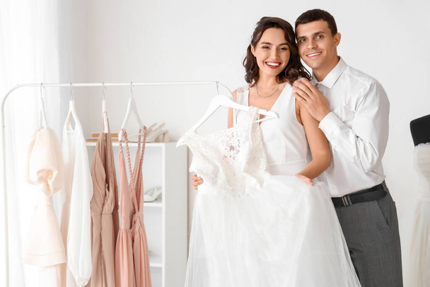 Young couple choosing wedding dress in office - Foto, imagen