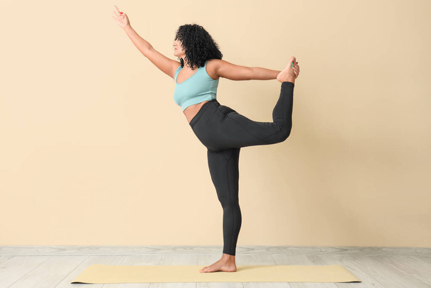 Sporty adult woman practicing yoga on beige background - Zdjęcie, obraz