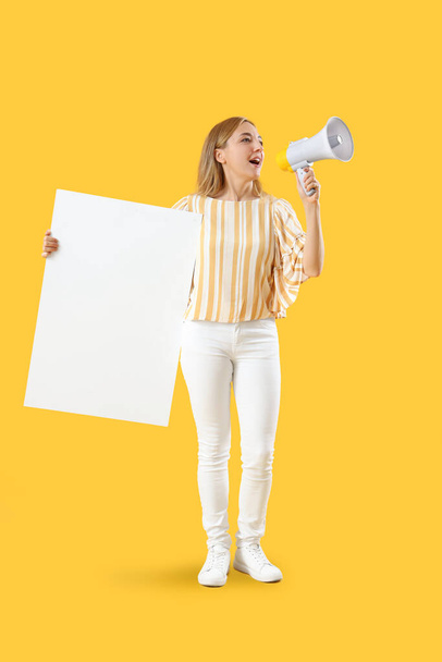 Mature woman with blank poster shouting into megaphone on yellow background - Zdjęcie, obraz