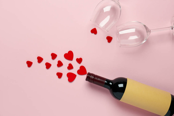 Bouteille de vin, verres et coeurs sur fond rose. Fête de la Saint-Valentin - Photo, image