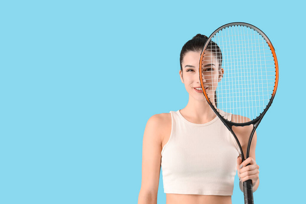Sporty young woman with tennis racket on blue background - Фото, изображение